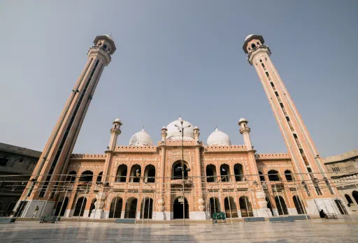 A grand mosque with tall minarets and domes, featuring intricate architecture, supported by Giving Hands.